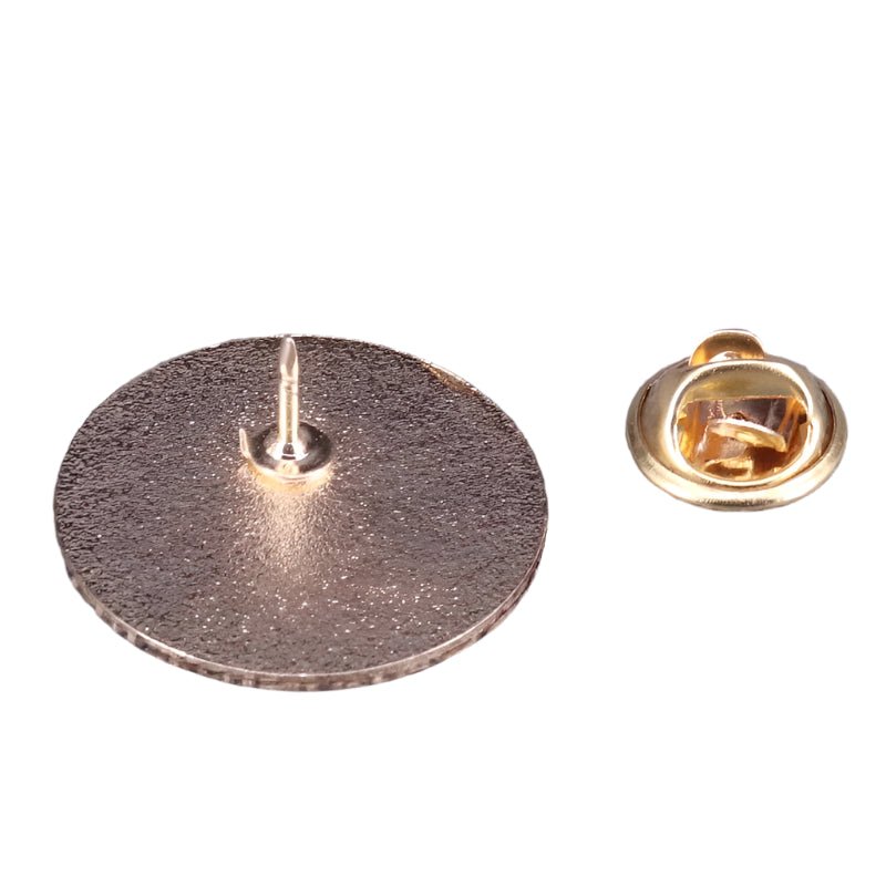 A close-up of a metallic round mental health pin with a sharp pointed back, shown beside its separate gold butterfly clutch fastener on a white background.