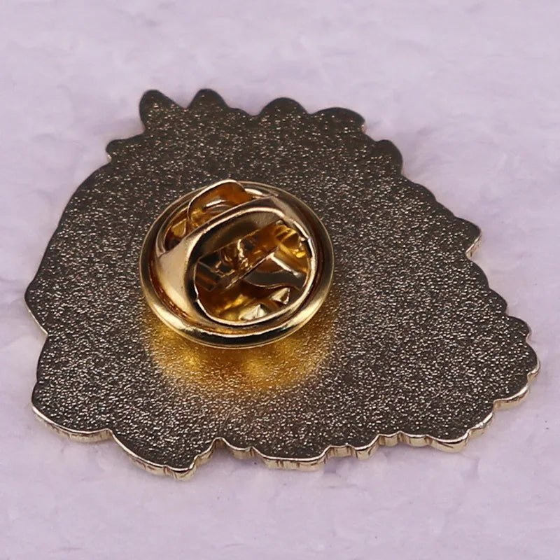 A close-up of the back of a metallic enamel pin with a gold butterfly clutch fastener, resting on a light, textured surface—ideal for fans of Skulls and Red Roses or anyone who loves a gothic bouquet aesthetic.