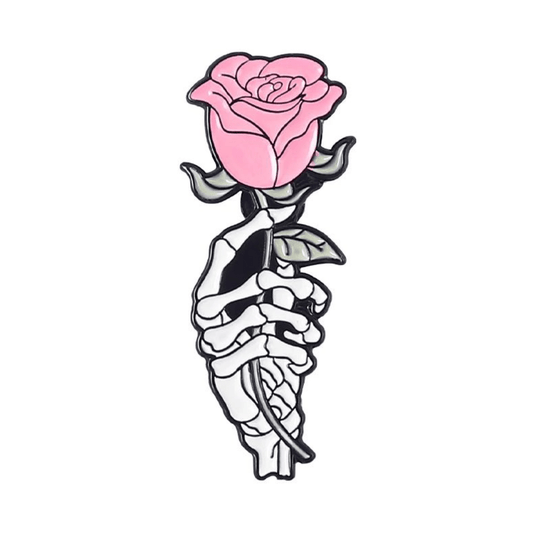 A skeleton hand holds a pink rose with green leaves on a white background—an ideal enamel pin design