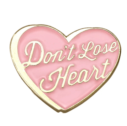 A gold and pink enamel heart-shaped pin featuring “Don’t Lose Heart” in elegant cursive—a sweet reminder of self-love.