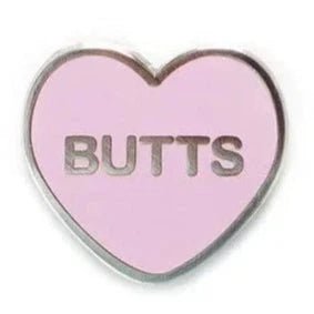 Add a playful touch to your pride style with the Gay Skate pink and silver enamel candy heart pin, featuring a bold BUTTS across the center—a fun heart-shaped accessory for any collection.