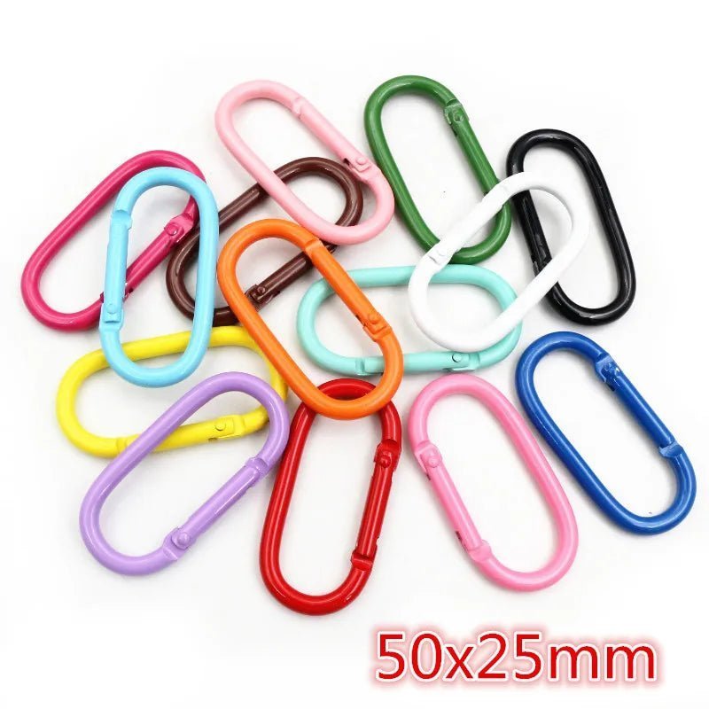 My Cutesy Era’s colorful oval plastic rainbow carabiners (50x25mm) are scattered on white in shades like red, pink, blue, green, and black—a vibrant queer accessory to express pride or style.