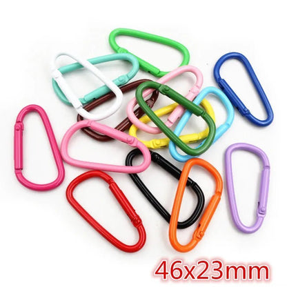 A pile of colorful My Cutesy Era rainbow carabiners in pink, red, blue, green, yellow, and black is shown. The 46x23mm size appears in red text—perfect as a fun queer accessory for the wlw community.