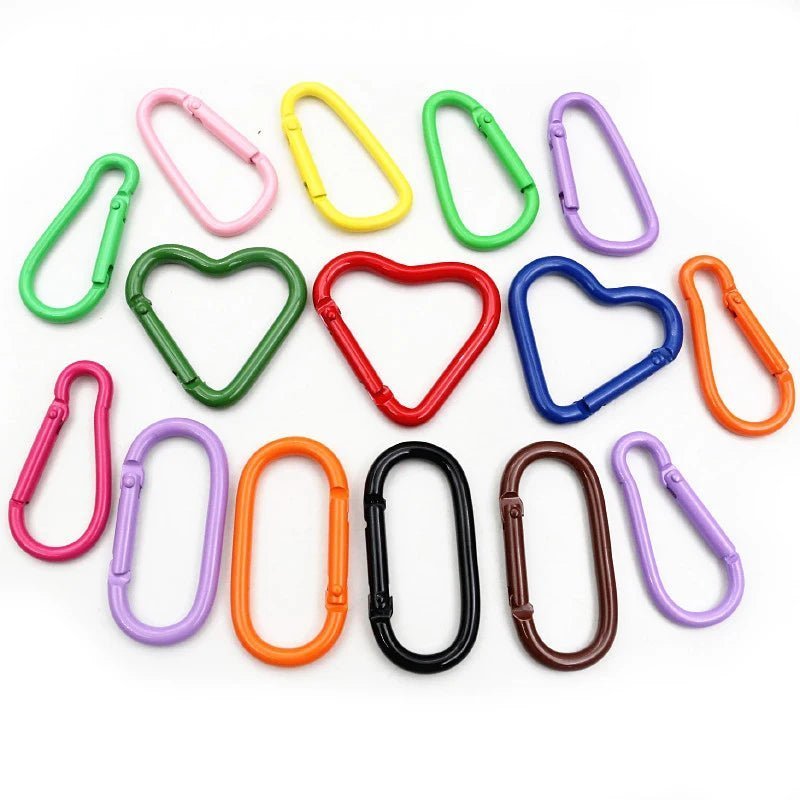 My Cutesy Era offers vibrant rainbow carabiners in heart, triangle, and oval shapes—arranged on a white background—making them the perfect queer accessory.