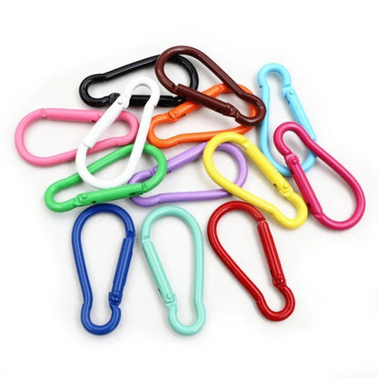 A colorful pile of My Cutesy Era rainbow carabiners—fun queer accessories in shades like red, blue, green, pink, yellow, and more—arranged on a white background.
