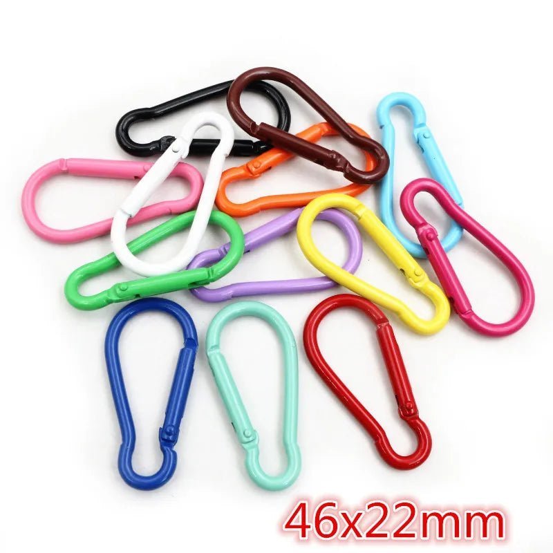 A vibrant assortment of My Cutesy Era rainbow carabiners in multiple sizes lies on a white background, with 46x22mm in red at the corner—an ideal queer accessory.