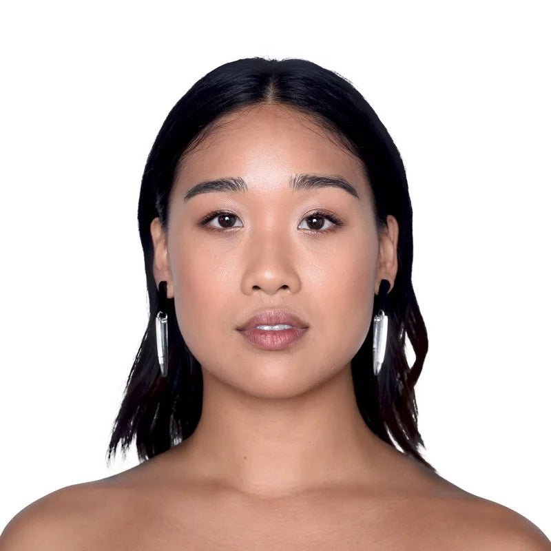 A woman with straight, shoulder-length dark hair and light makeup wears Kiss Me Later’s striking knife earrings, looking directly at the camera with a neutral expression against a plain white background.