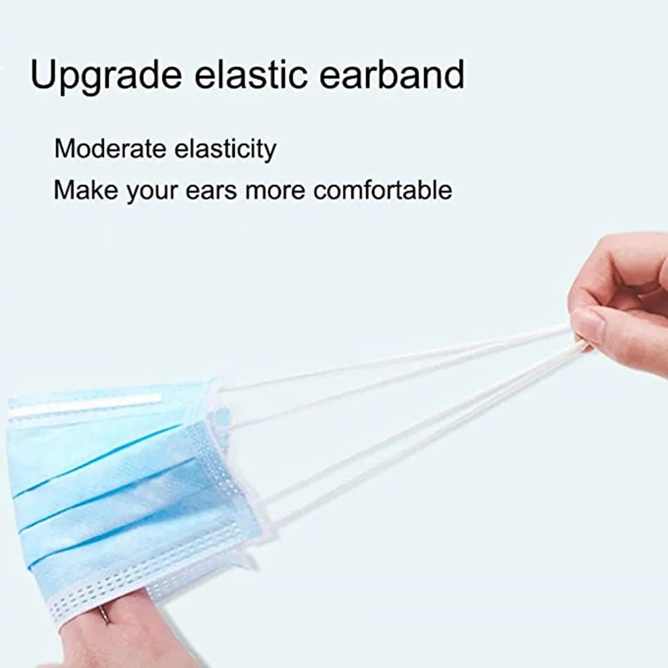 A hand stretches the elastic earbands of a blue Kiss Me Later triple-layer face mask. Text reads: Upgraded elastic earbands—moderate stretch for extra comfort. Ideal for disposable medical face mask needs.