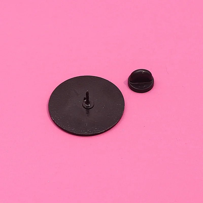 fundraising enamel pin with its matching round clutch backing is displayed on a bright pink background. The pin lies flat, showing the back post, while the clutch is placed alongside it.