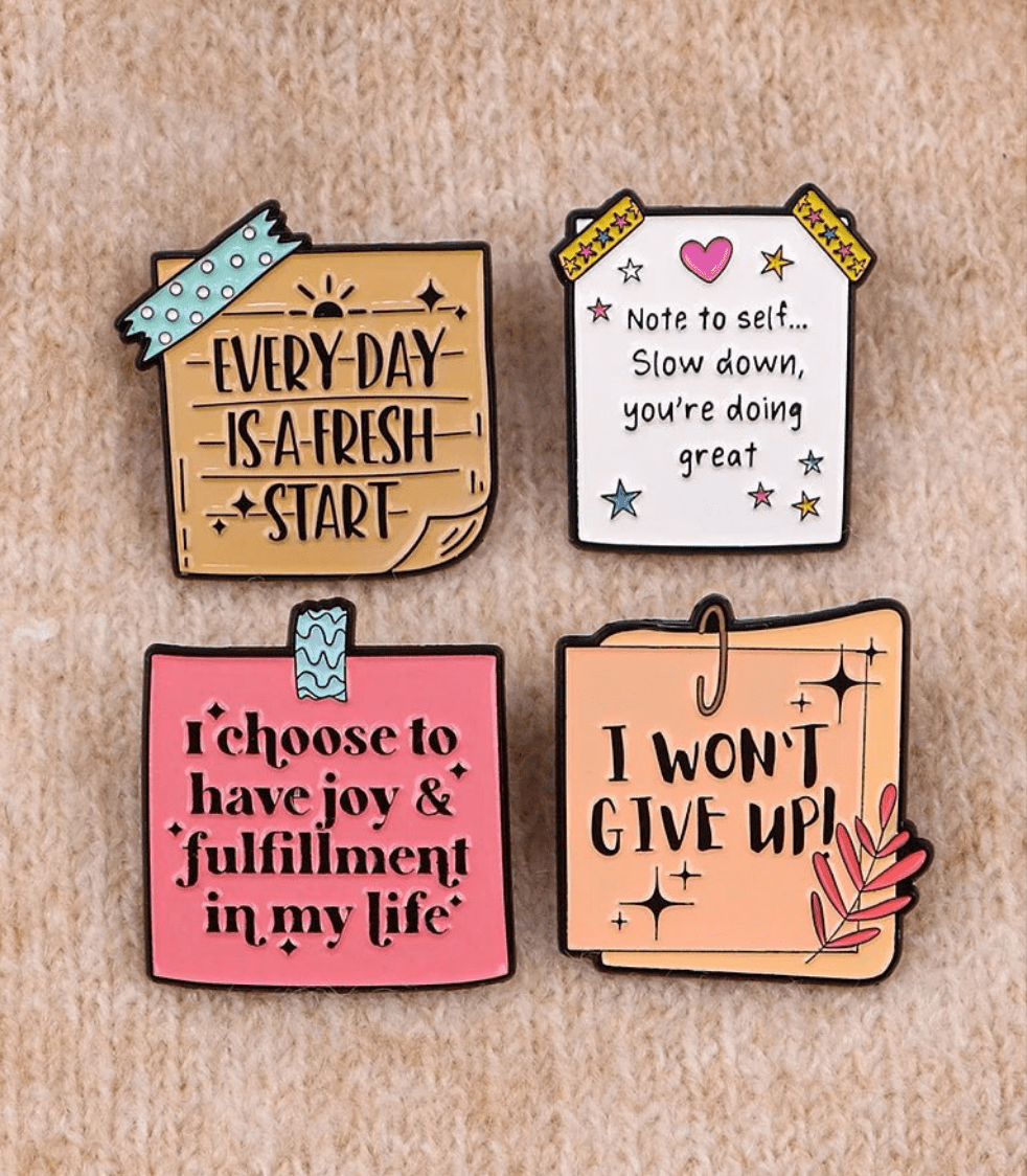 Four colorful pins on beige share uplifting messages: Every day is a fresh start, Note to self... Slow down, youre doing great, I choose joy & fulfilment in my life, and I won’t give up!.
