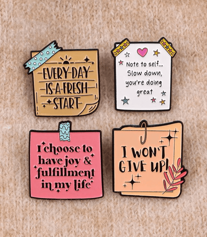Four colorful pins on beige share uplifting messages: Every day is a fresh start, Note to self... Slow down, youre doing great, I choose joy & fulfilment in my life, and I won’t give up!.