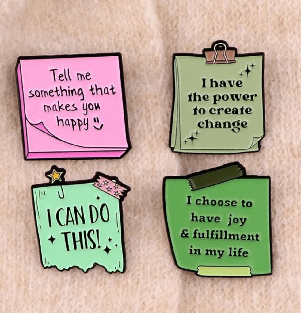 A set of four colorful pins, styled as sticky notes, feature uplifting messages like “Tell me something that makes you happy” and “I choose to have joy & fulfillment in my life.”.