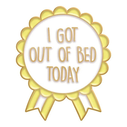 A gold and white award ribbon enamel pin with “I GOT OUT OF BED TODAY” in bold gold letters—a quirky, fun accessory for any Cute But Psycho fan.