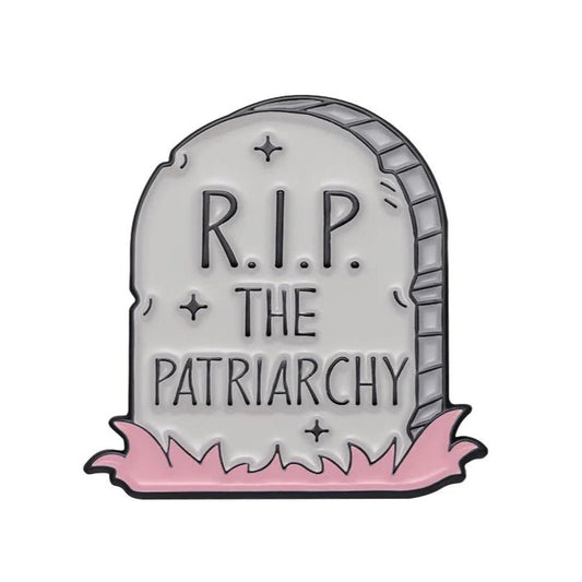 Patriarchy Tombstone enamel pin features R.I.P. THE PATRIARCHY in a cartoon style with pink grass—ideal for fans of feminist pins.