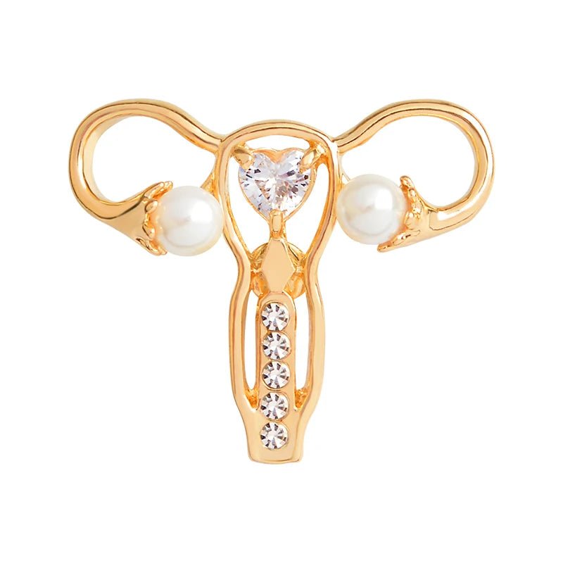 Gold uterus ovary pin brooch features a heart-shaped gem center, pearl-like beads on each side, and five small round gems below—a unique feminist gift.