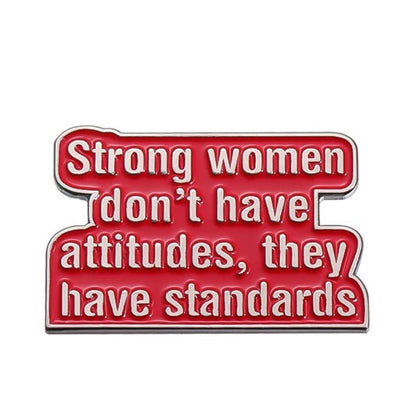 A red enamel pin by My Cutesy Era with white text: Strong women don’t have attitudes, they have standards. Perfect for empowered women gifts or any fan of feminist enamel pins.