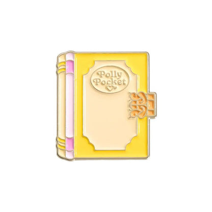 My Cutesy Era enamel pin: closed yellow book with pink spine, gold accents, and "Polly Pocket" on the cover in a decorative frame—perfect as a charming accessory or gift for book lovers and bookworms.