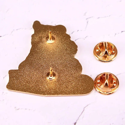 Raven pin shown from the back with two pin posts and butterfly clasps on a white textured surface, evokes the mysterious silhouette of a raven.