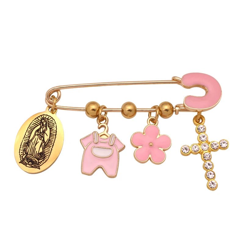 A Kiss Me Later gold Christian baby pin brooch featuring five dangling charms: an oval Virgin Mary medallion, pink overalls, a pink flower, a diamante cross, and a pink horseshoe.