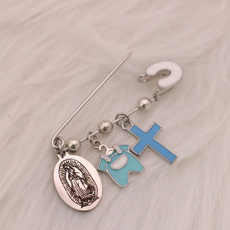 The Kiss Me Later silver Virgin Mary brooch showcases four dangling charms—an oval medal, a blue baby icon, a blue enamel cross, and a white question mark—displayed on soft white fur.