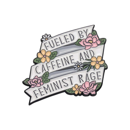 Enamel pin with a white ribbon stating Fueled by caffeine and feminist rage, embellished with pink/yellow flowers and green leaves—a bold, standout accessory for any feminist pin collection.