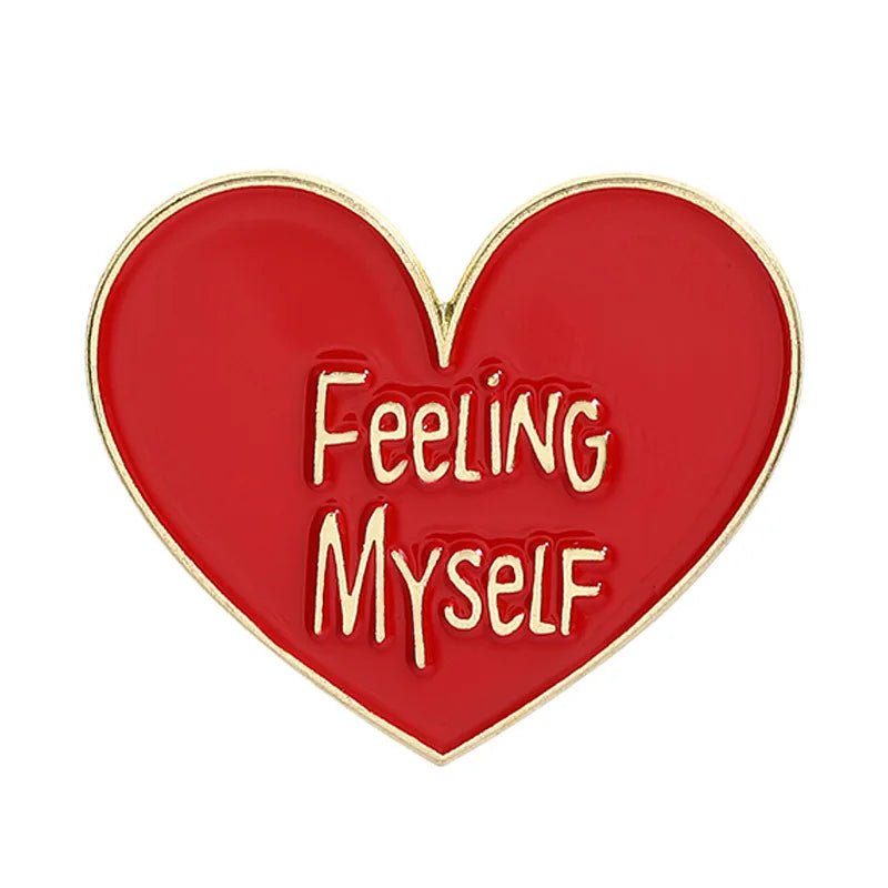 Heart-shaped enamel pin features a bold red and gold design, outlined in gold, with FEELING MYSELF in playful gold text at the center.