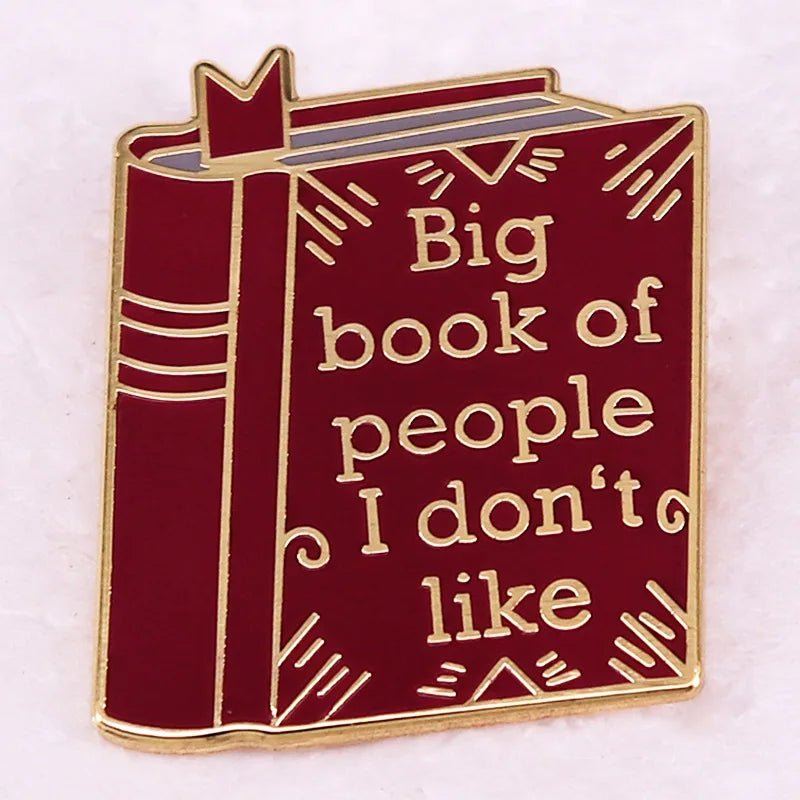 Red enamel pin is shaped like a book with gold outlines and the phrase Big book of people I dont like—a witty, playful accessory for romance readers or anyone who loves unique bookish badges.