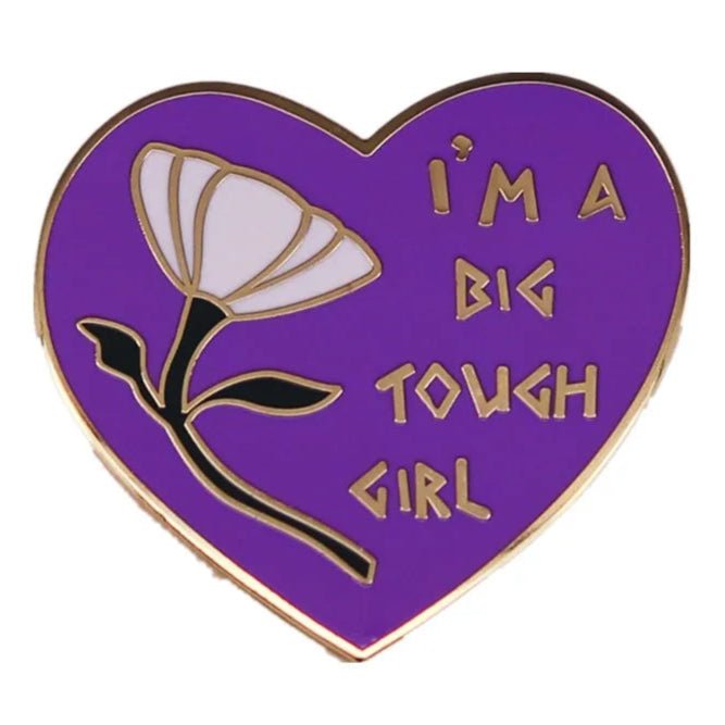 The My Cutesy Era heart pin features a white flower and the words IM A BIG TOUGH GIRL in gold lettering on a purple background.