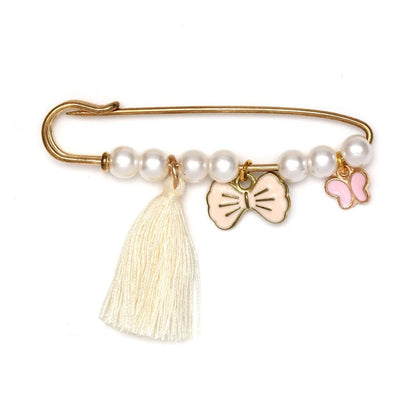 Kiss Me Laters gold safety pin brooch features five white pearls, a cream tassel, a cream bow charm, and a pink butterfly charm—an adorable accessory, perfect as a baby shower gift.
