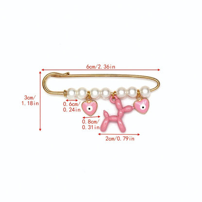 Kiss Me Laters gold evil eye pin features pearl beads and four pink charms—three heart-shaped eyes (0.6 cm each) and a 2 cm balloon dog. The pin measures 6 cm long by 3 cm tall—a cute baby shower gift!.