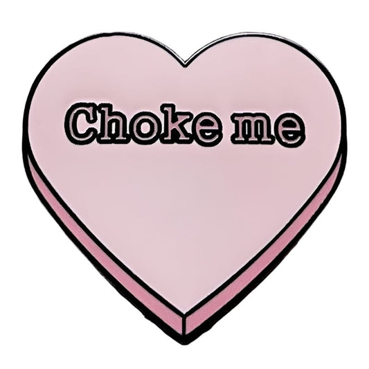 A pink heart enamel pin from My Cutesy Era with Choke me written in bold black letters.
