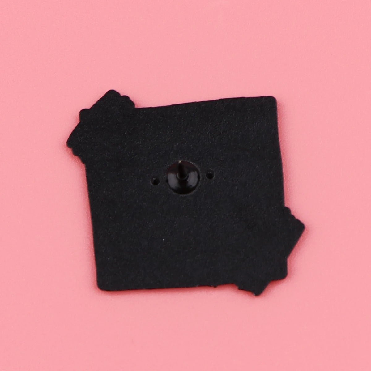 A black square pin with jagged edges  rests on a pink background. Its shiny center symbolizes self-empowerment, making it a unique accessory for daily positive affirmations.