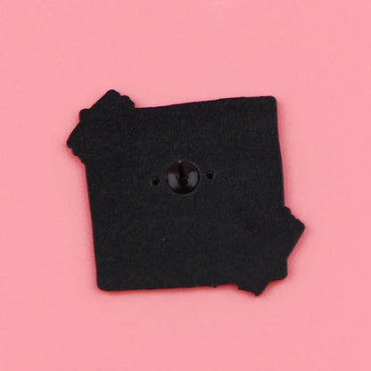 A black square pin with jagged edges  rests on a pink background. Its shiny center symbolizes self-empowerment, making it a unique accessory for daily positive affirmations.