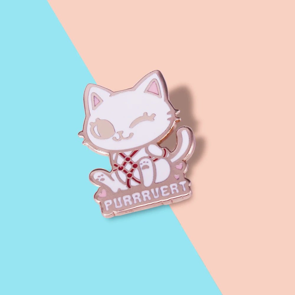Enamel pin: a cute white cartoon cat with a red bow and heart-shaped eye patch sits above PURRAVERT on a split pastel blue and peach background.