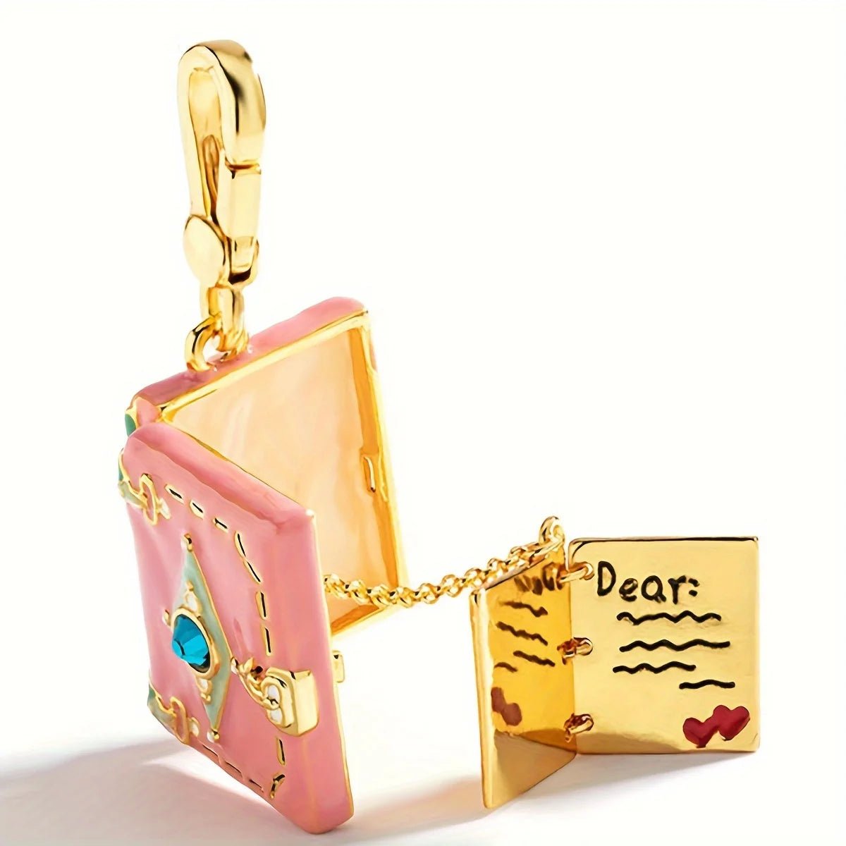 Gold pink enamel book pendant features a blue gem on the cover and opens to reveal a tiny page with “Dear,” lines, and red heart illustrations—just like a miniature love letter on a chain.