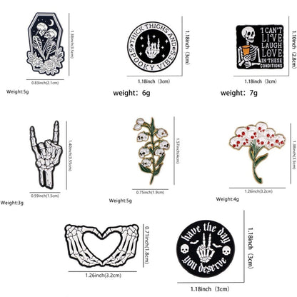 Kiss Me Later presents a set of nine enamel pins with skeletons, flowers, hand signs (including a skeleton hand pin), and positive messages—each labeled with size and weight—displayed on white for spooky vibes.
