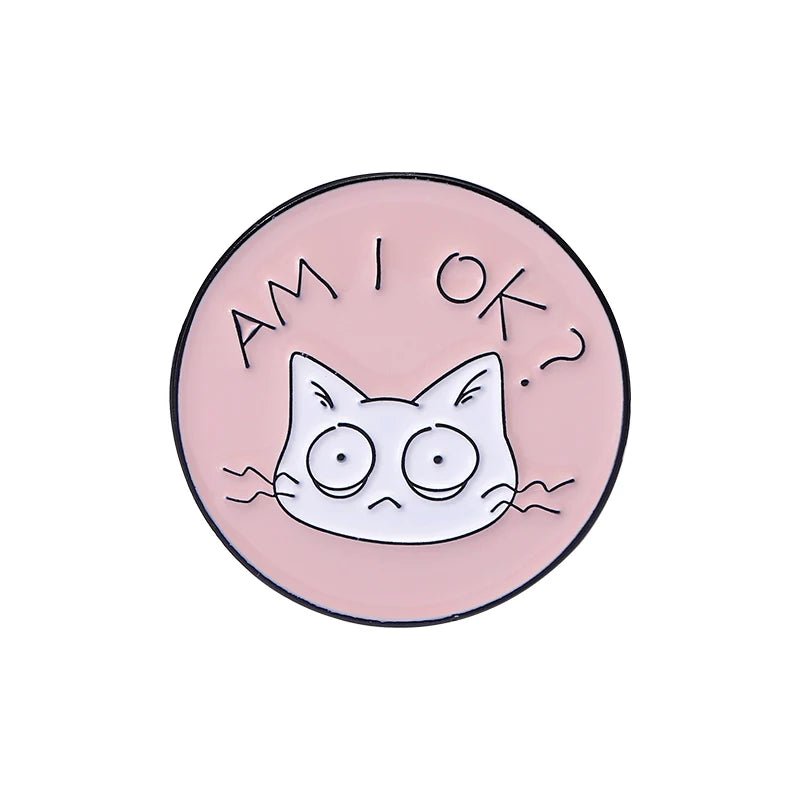 Round pink cat pin shows a wide-eyed cartoon feline with AM I OK? above its head. This quirky accessory features an anxious cat, adding charm and personality to your style.