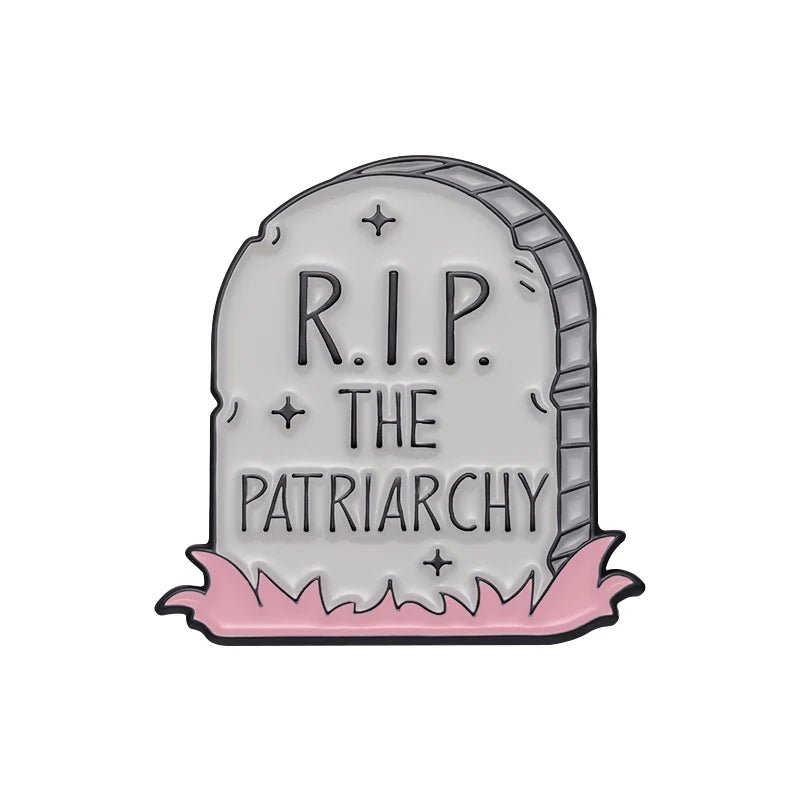 A gray tombstone that reads R.I.P. THE PATRIARCHY stands on pink grass with a tiny love heart enamel pin at the base, set against a white background. 