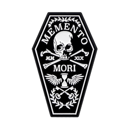 A black coffin-shaped patch by Kiss Me Later featuring a skull and crossbones, Memento Mori, laurel branches, crossed keys, Roman numerals MM XIX, a winged hourglass—spooky vibes perfect with your skeleton hand enamel pin.
