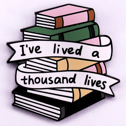 Enamel pin features a stack of colorful books with a ribbon that reads Ive lived a thousand lives. Perfect for romance readers and book lovers who love collecting unique badges.