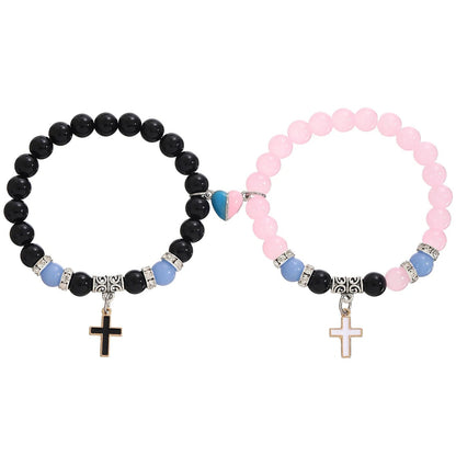 Kiss Me Later set of two beaded bracelets: one with black beads and gold cross charm, the other pink with gold cross, both accented by blue/silver beads and a blue-pink heart—an ideal baptism gift.