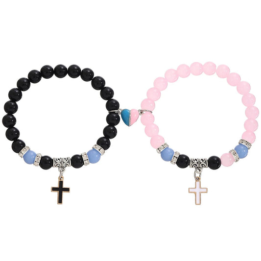 Kiss Me Later set of two beaded bracelets: one with black beads and gold cross charm, the other pink with gold cross, both accented by blue/silver beads and a blue-pink heart—an ideal baptism gift.