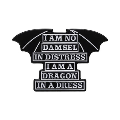 Black enamel pin features dragon wings and white text: “I am no damsel in distress, I am a dragon in a dress”—a bold addition to any feminist pin collection.