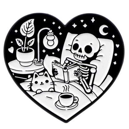 Kiss Me Later: A heart-shaped black and white print gives spooky vibes—thick-thighed skeleton reading in bed with a cat, tea, lamp, potted plant, and a crescent moon with stars glowing in the background.
