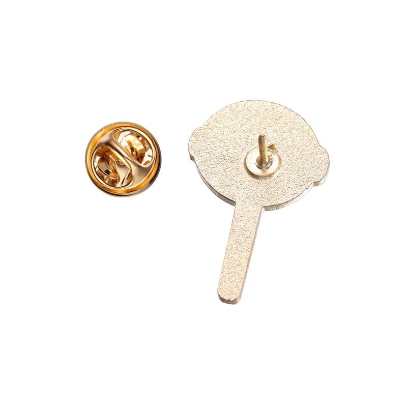 Gold-colored lollipop enamel pin is displayed from the back, showing its textured finish and stick-like extension, with a round butterfly clutch pin backing beside it on a white background.