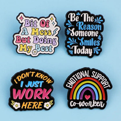 Set of four colorful enamel pins features positive phrases—like “Bit Of A Mess But Doing My Best” and “Emotional Support Co-worker” with a rainbow—perfect for motivation or as a thoughtful gift.