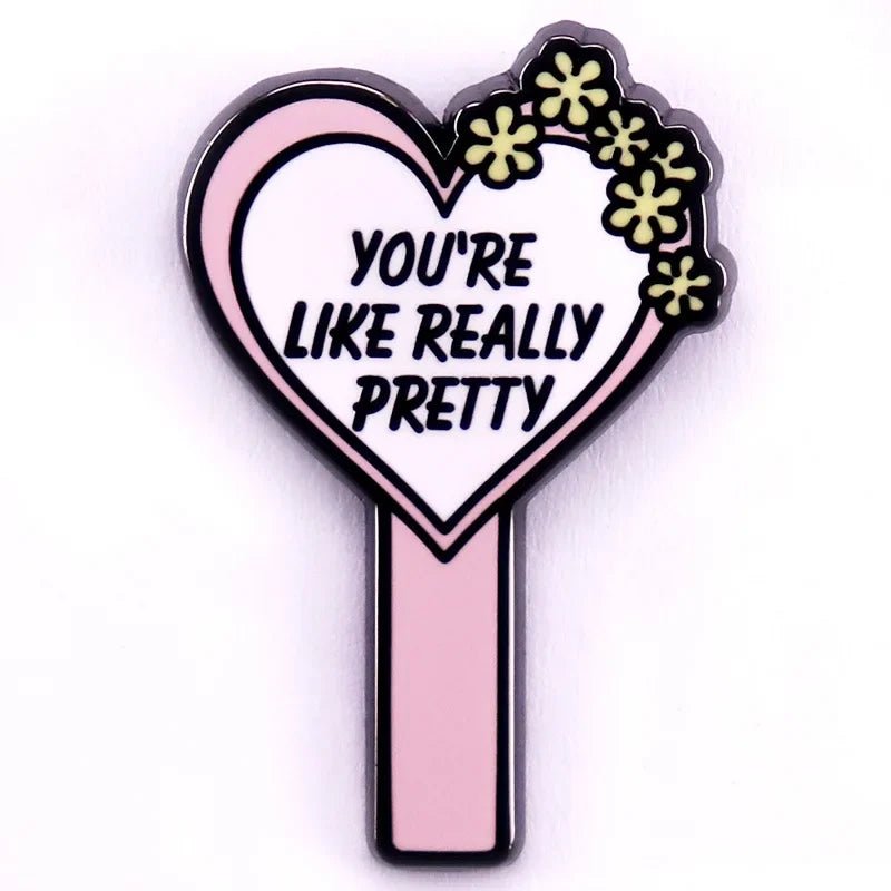 Enamel pin features a pink love heart decorated with yellow flowers and the phrase YOURE LIKE REALLY PRETTY in the center.