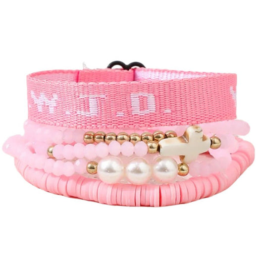 The Kiss Me Later pink bracelet stack features pearls, gold beads, a white cross, and a woven W.W.J.D. bracelet for a chic layered look.