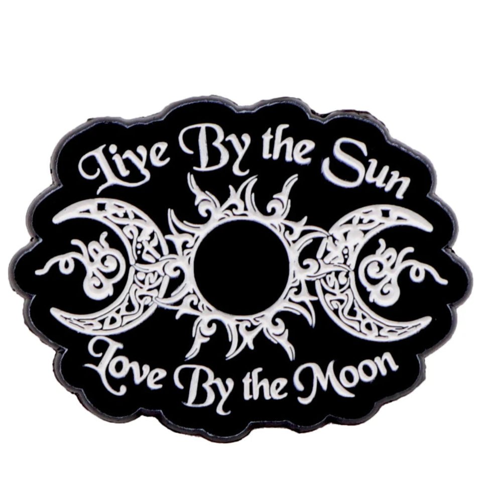 The Kiss Me Later black and white emblem features an ornate sun and moon design with the text Live By the Sun, Love By the Moon. Perfect for fans of skeleton hand enamel pins and unique celestial style.