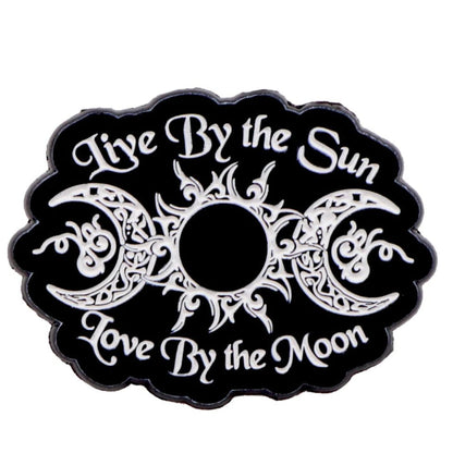 The Kiss Me Later black and white emblem features an ornate sun and moon design with the text Live By the Sun, Love By the Moon. Perfect for fans of skeleton hand enamel pins and unique celestial style.